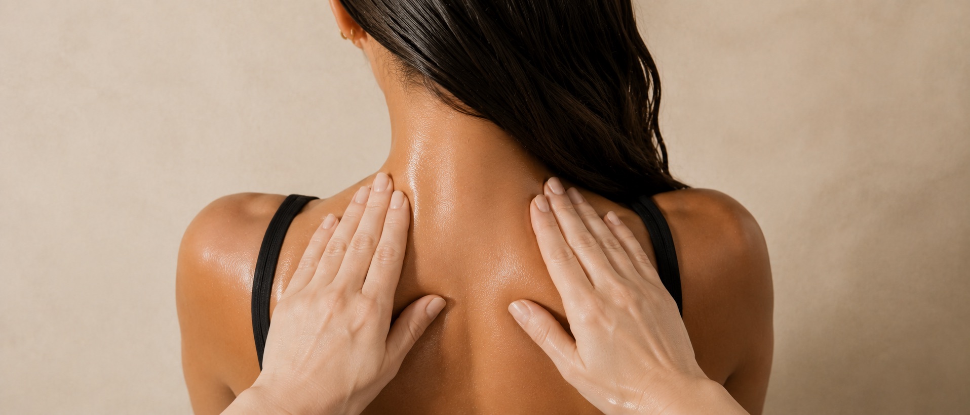 Seen from behind, the practitioner’s flat hands sweeping down either side of a client’s neck and shoulders