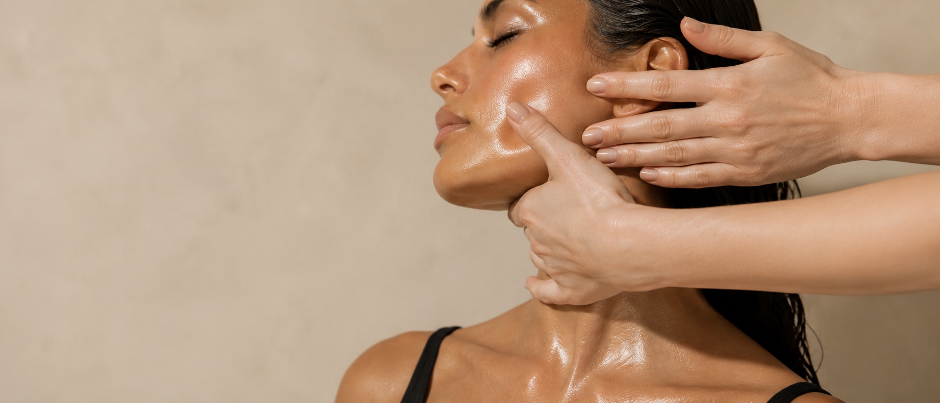 Gloved hands working along a client's cheek and jaw during a facial massage