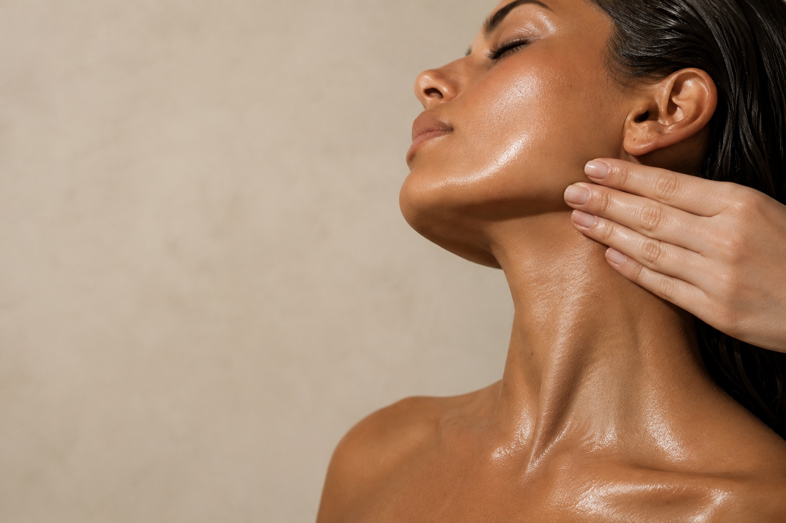 A practitioner's hand pressed along the jaw and neck, head tipped back